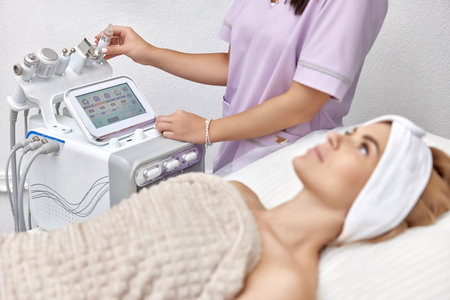 female beautician using cosmetology equipment in modern aesthetic clinic.の写真素材