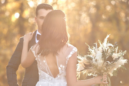 beautiful bride in white wedding dress and groom standing outdoor on natural background in sunny day. copy spaceの写真素材