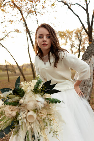 beautiful happy bride holding wedding autumn bouquet in natureの写真素材
