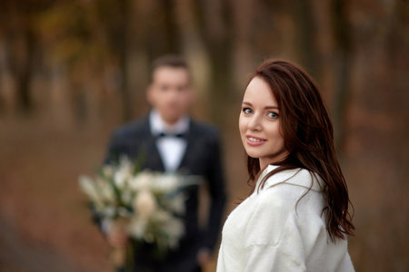 portrait of beautiful happy bride and blur groom holding wedding autumn bouquet on the backgroundの写真素材