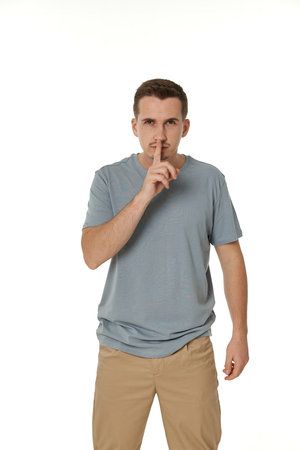 Young man showing sign of silence gesture on white backgroundの写真素材