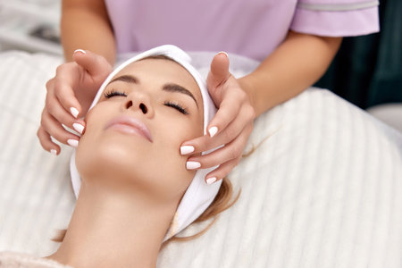 Beautiful woman getting face massage treatment in beauty salon. girl enjoys this procedure.の写真素材