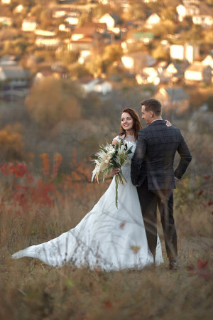 beautiful sensual bride in white wedding dress and groom standing outdoor on natural backgroundの写真素材