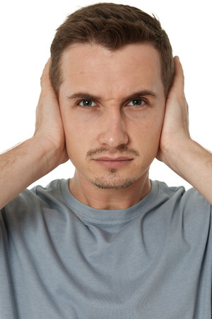 caucasian man in t-shirt covers ears with hands on white backgroundの写真素材