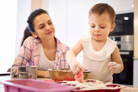 mother and little baby girl preparing the dough in the kitchen, bake cookies. happy time togetherの写真素材
