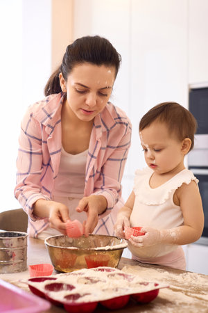 mother and little baby girl preparing the dough in the kitchen, bake cookies. happy time togetherの写真素材