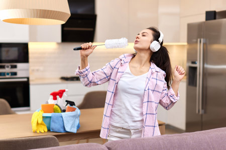 young happy housewife woman singing and cleaning her home, girl enjoying domestic work.の写真素材