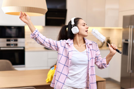 young happy housewife woman singing and cleaning her home, girl enjoying domestic work.の写真素材