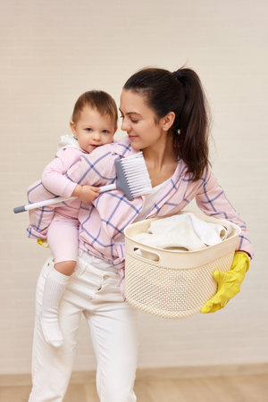 happy mother housewife is holding cute baby girl and basket with laundry , Happy familyの写真素材