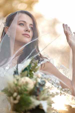 beautiful happy bride in veil holding wedding autumn bouquetの写真素材