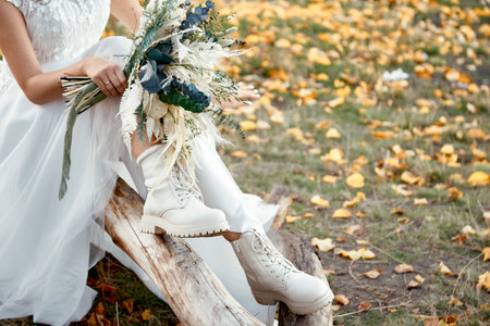 bride wearing white boots holding beautiful autumn bouquet. copy spaceの写真素材