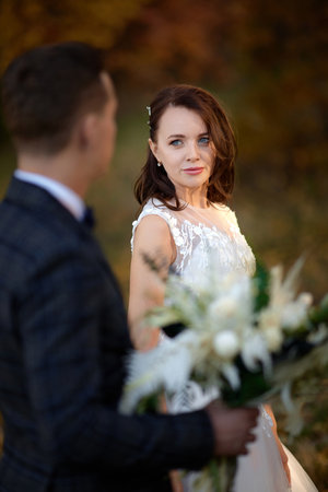 beautiful sensual bride in white wedding dress and groom standing outdoor on natural backgroundの写真素材