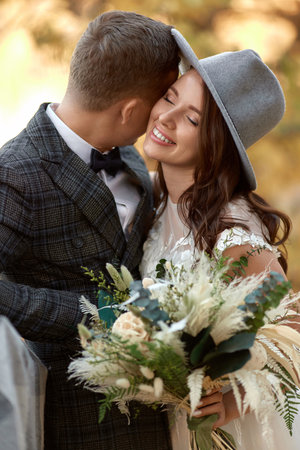 beautiful happy stylish bride in hat and groom laughing outdoorの写真素材