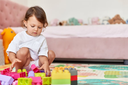 cute baby girl playing with colorful toys bricks at home, copy spaceの写真素材