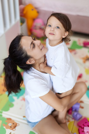 happy mother with cute baby girl in white t-shirt having fun togetherの写真素材