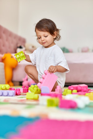 cute baby girl playing with colorful toys bricks at homeの写真素材