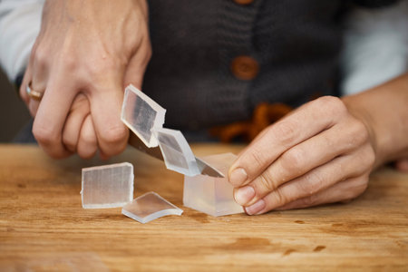 close-up of hands of mother helps her little child girl using knife for preparing hand-made soap, art workshops for children.の写真素材