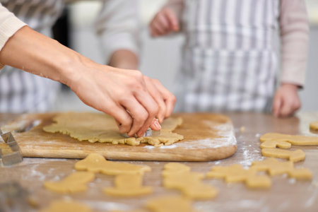 hands of mother and little child daughter cutting cookies of raw gingerbread dough in kitchen, Christmas traditionsの写真素材