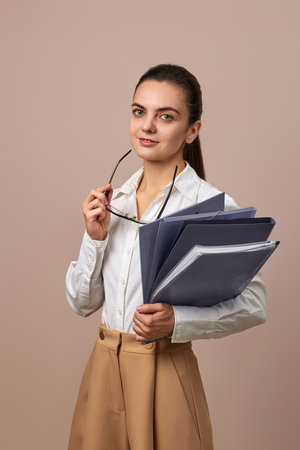 smiling businesswoman holding folders. Confident woman in glasses and white shirt looking at the...