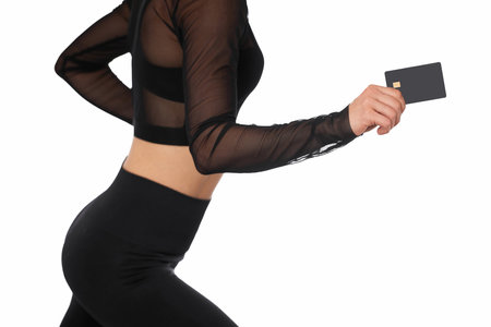 athletic fitness woman in sport wear holding black credit card on white background. payment onlineの写真素材