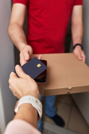 Woman using black credit card for payment of Pizza delivery man, close-upの写真素材