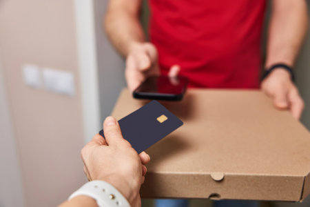 Woman using black credit card for payment of Pizza delivery man, close-upの写真素材