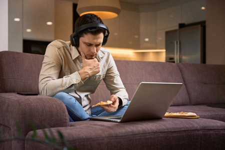 Freelancer man suffer from headache and working with laptop at homeの写真素材