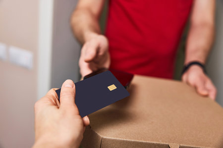 Woman using black credit card for payment of Pizza delivery man, close-upの写真素材