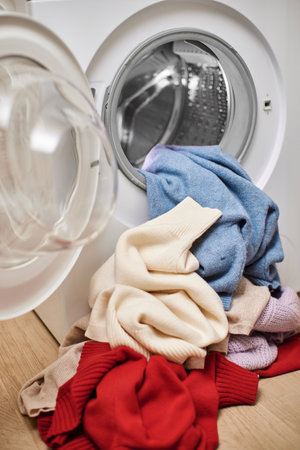 Colorful and white wool laundry and washing machine with open door. Close up.の写真素材