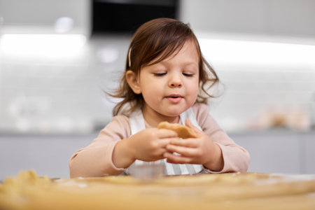 cute happy little child girl cutting gingerbread cookies with a cookie cutter in kitchen. festive gingerbread cookiesの写真素材