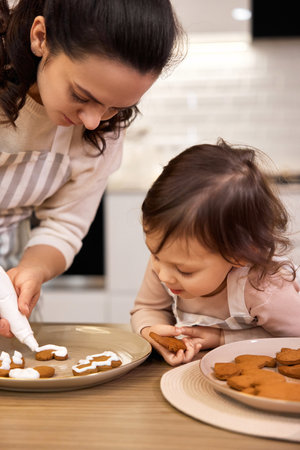 happy mother and little child girl bake cookies on the kitchen at homeの写真素材