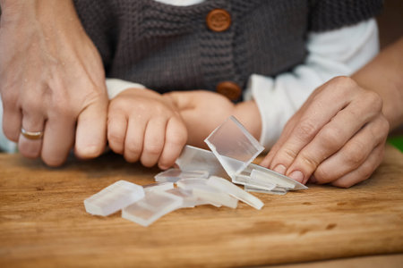 close-up of hands of mother helps her little child girl using for preparing hand-made soap, art workshops for children.の写真素材