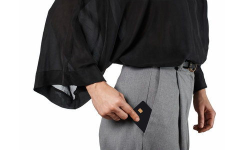 Modern business woman putting black premium credit bank card in grey pants pocket on white background. Money financeの写真素材