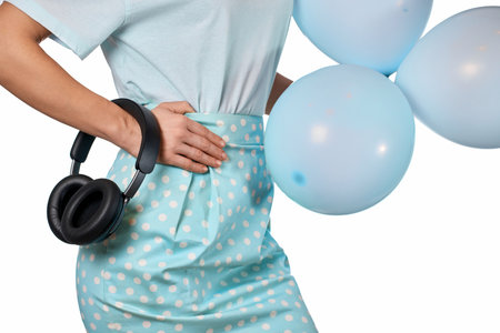 Female hand holding blue balloon and headphones on white backgroundの写真素材