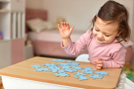 Cute little child girl playing with puzzle, copy spaceの写真素材