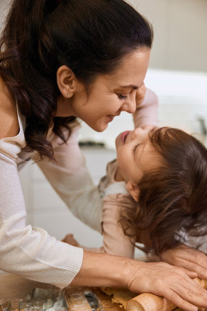 Happy mother and smiling cute little child daughter rolling dough for homemade pastry.の写真素材