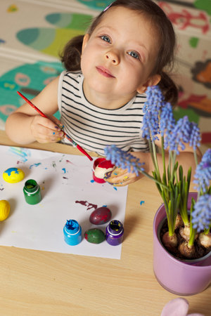 Little child girl paint Easter eggs at home. kid is preparing for Easter.の写真素材