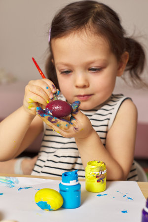 Little child girl paint Easter eggs at home. kid is preparing for Easter.の写真素材