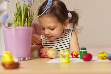 Little child girl paint Easter eggs at home. kid is preparing for Easter.の写真素材