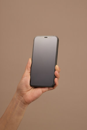woman holding smartphone with blank black screen on beige background, mockupの写真素材
