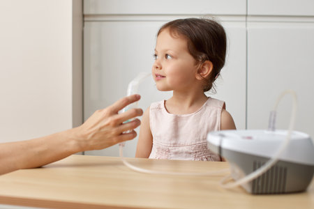 woman makes inhalation to cute toddler child girl at homeの写真素材