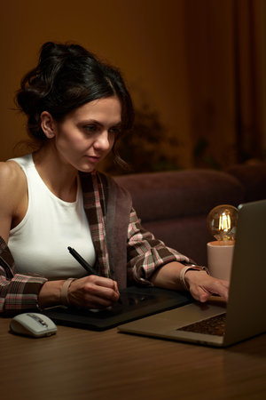 beautiful graphic designer woman working at home office remotely using digital graphic tablet and laptopの写真素材