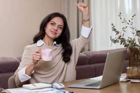 Happy relaxed woman using laptop while working remotely from home in living roomの写真素材