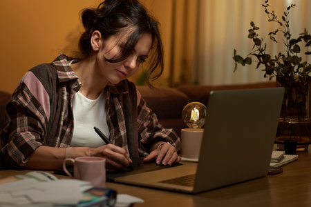 beautiful professional female retoucher woman working at home workspace using digital graphic tablet and laptopの写真素材