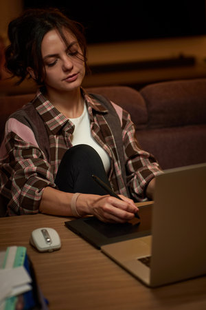beautiful graphic designer woman working at home office remotely using digital graphic tablet and laptopの写真素材