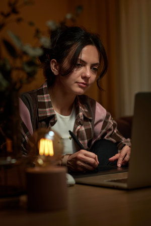 beautiful professional female retoucher woman working at home workspace using digital graphic tablet and laptopの写真素材