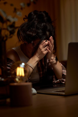 tired graphic designer woman working overtime at home office remotely using digital graphic tablet and laptopの写真素材