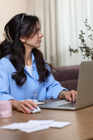 portrait of woman in blue shirt working using laptop in home officeの写真素材