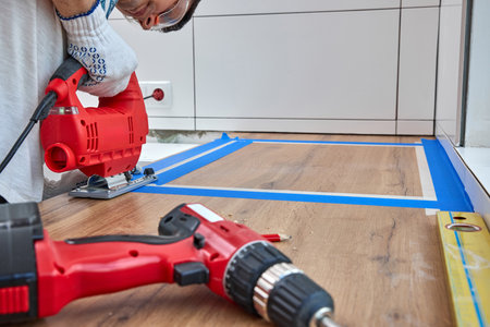 repairman using electric jigsaw and cutting hole for the sink in the kitchen countertops, Woodworking and carpentry conceptの写真素材