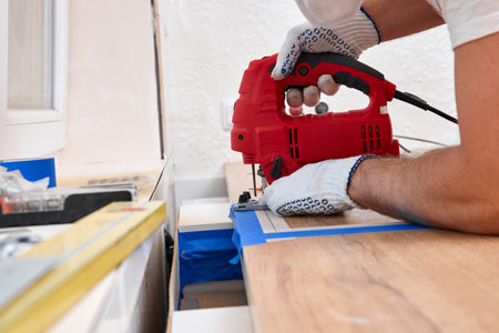 repairman using electric jigsaw and cutting hole for the sink in the kitchen countertopsの写真素材